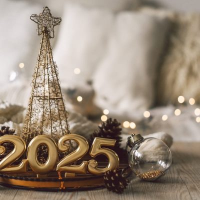 The arrangement features golden numbers representing 2025, lit candles, and a Christmas decor, creating a festive atmosphere in a cozy setting perfect for New Year celebrations.